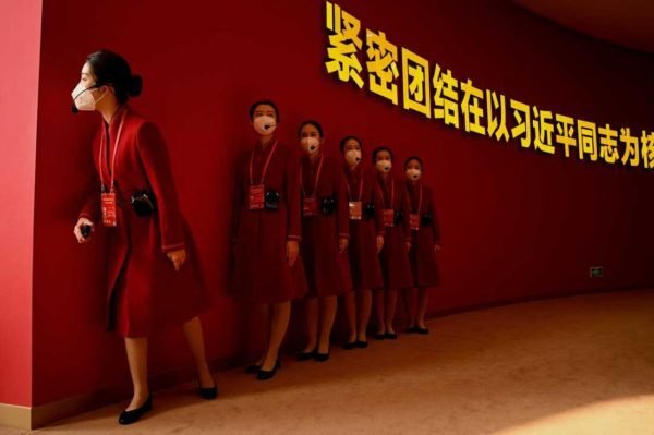 TOPSHOT - Attendants wait for visitors to the the exhibition entitled "Forging Ahead in the New Era", showing the country's achievements during his past two terms, at the Beijing Exhibition Center in Beijing on October 12, 2022, ahead of the 20th Communist Party Congress meeting. (Photo by Noel CELIS / AFP) (Photo by NOEL CELIS/AFP via Getty Images)